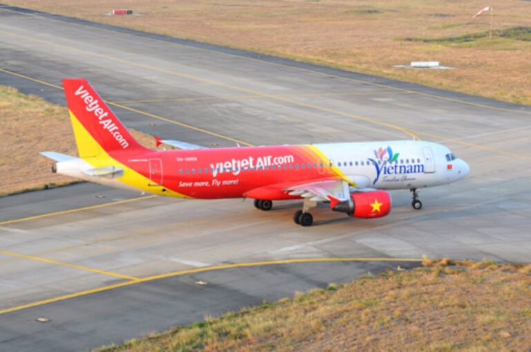 VietJet Air passenger jet on a taxiway, red and yellow gradient tail, white fuselage with 'vietjetAir.com' lettering.