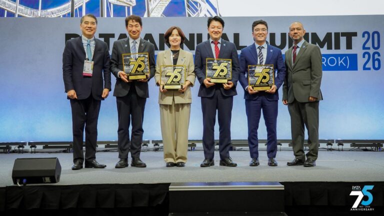 Group of six professionals on stage posing with 75th anniversary plaques at a formal summit event.