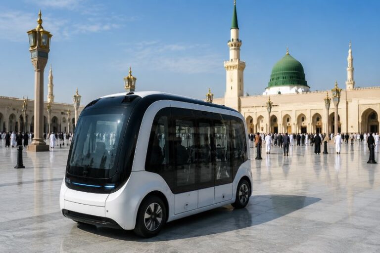 White autonomous shuttle parked in a wide marble plaza with a green-domed mosque in the background.