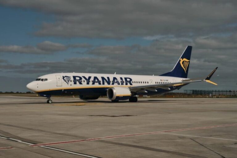 Ryanair Boeing 737 on the tarmac with white fuselage, blue logo lettering, and a dark blue tail with a yellow harp.