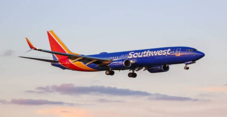 Southwest Airlines jet in blue livery taking off against a pastel sky.