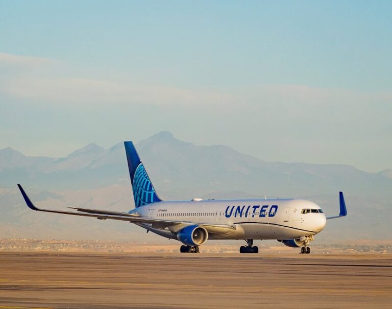 United Airlines plane on the runway with distant mountains in the background, desert landscape nearby