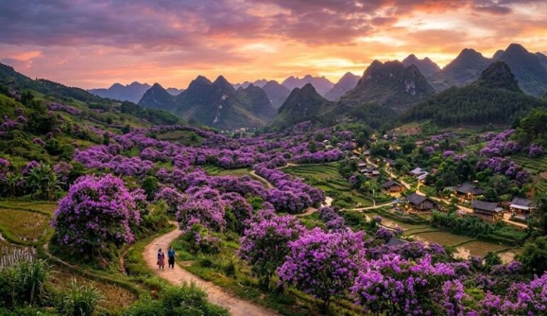 Sunset over a valley with purple jacaranda trees, green hills, and a winding dirt path where two people walk toward a small village nestled among lantern-lit houses.