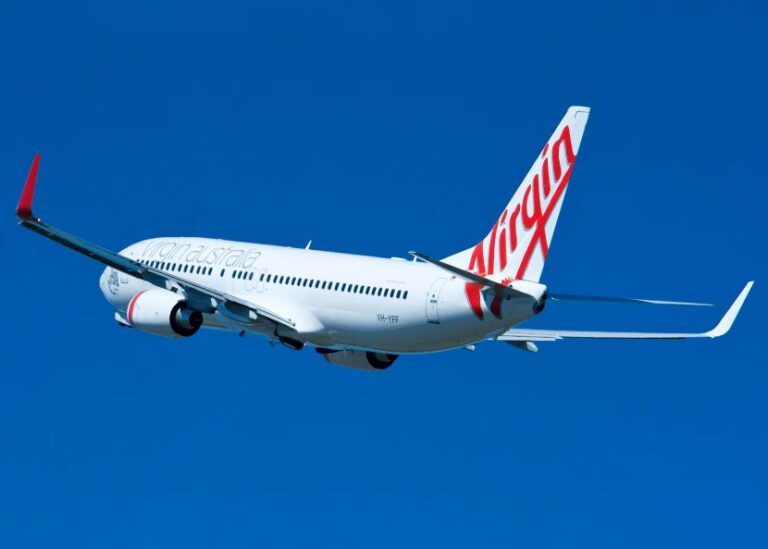 Virgin Australia passenger jet in clear blue sky during flight.