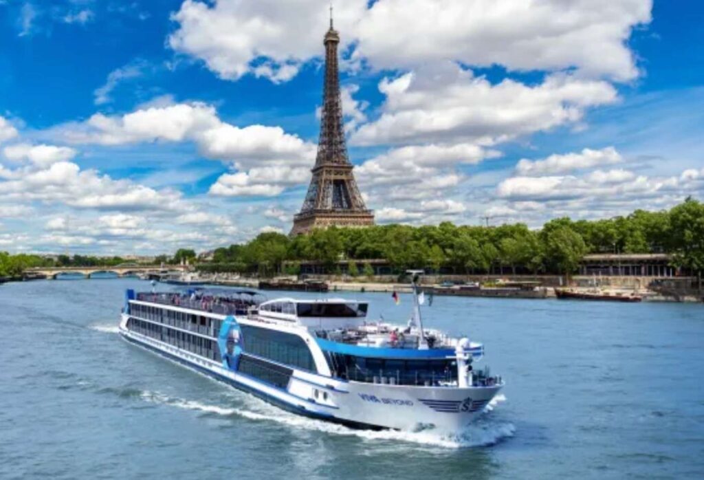 Sightseeing river cruise boat on the Seine with the Eiffel Tower in the background under a blue, cloudy sky