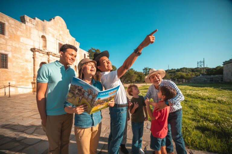 Group of friends on a sunny sightseeing tour outside a stone fortress; one man points ahead while others smile. (Informative)