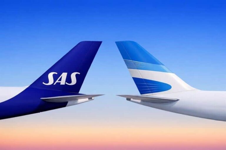 Two airplane tails touch mid-air against a sunset gradient; SAS logo on the left tail.