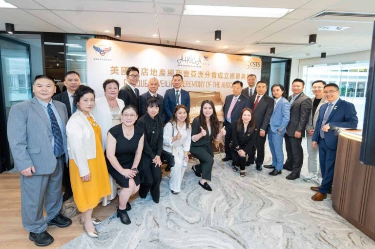 Group of 20+ professionals in suits and dresses posing for a ceremony photo in a modern office lobby.