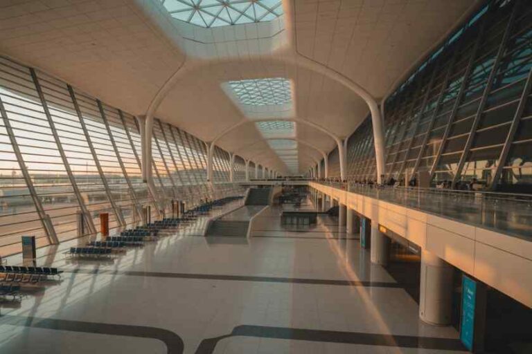 Interior of a spacious modern airport terminal with skylight panels and curved white arches.