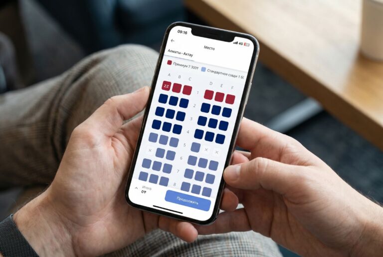 Phone held in hands showing a theater seating map with red premium and blue standard seats in an app page (Russian UI).