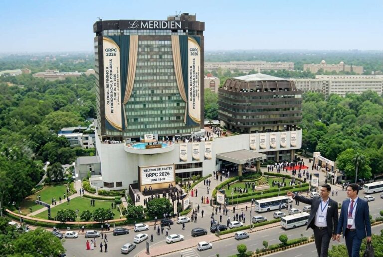 Aerial view of Le Meridien hotel hosting GRPC 2026, with large banners, crowds of delegates, and two suited men in the foreground.