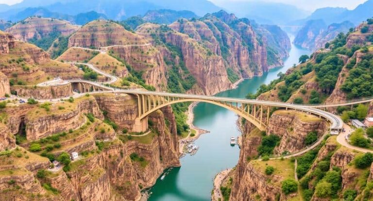 Bridge spanning a deep canyon over a winding river, surrounded by rugged cliffs and green hills.