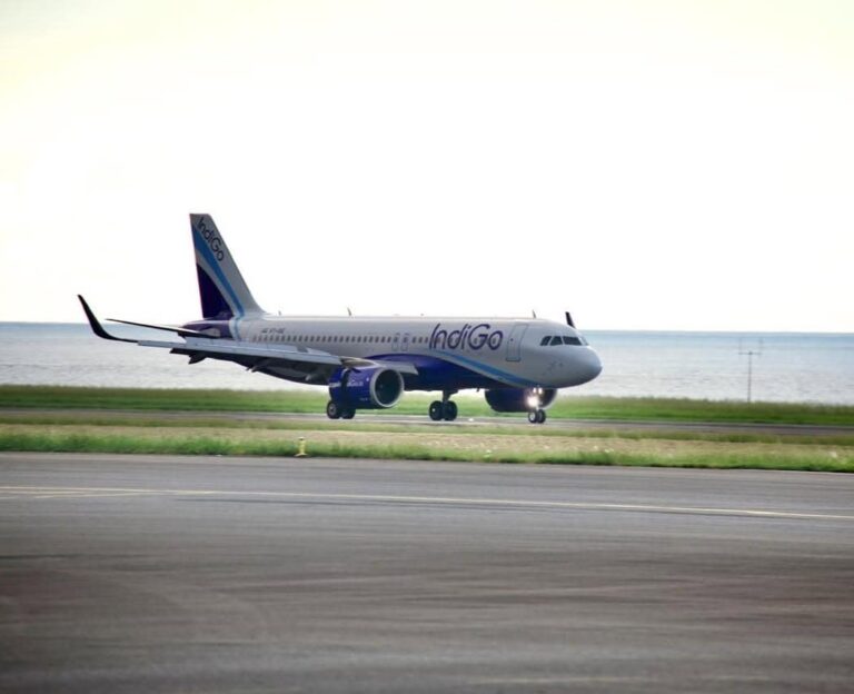 IndiGo passenger airplane taxiing on a runway with the sea in the background.