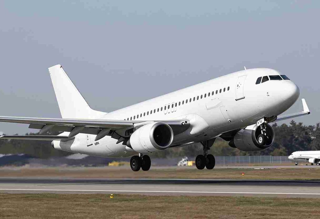 White commercial airliner lifting off the runway during takeoff at an airport.
