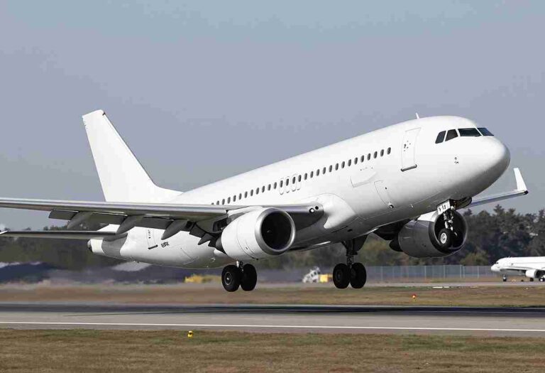 White commercial airliner lifting off the runway during takeoff at an airport.