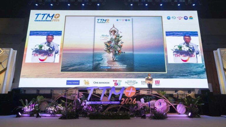 Large conference stage with a giant screen showing the TTM+ 2026 poster over an ocean sunset, a speaker at the podium, and sponsor logos along the front.