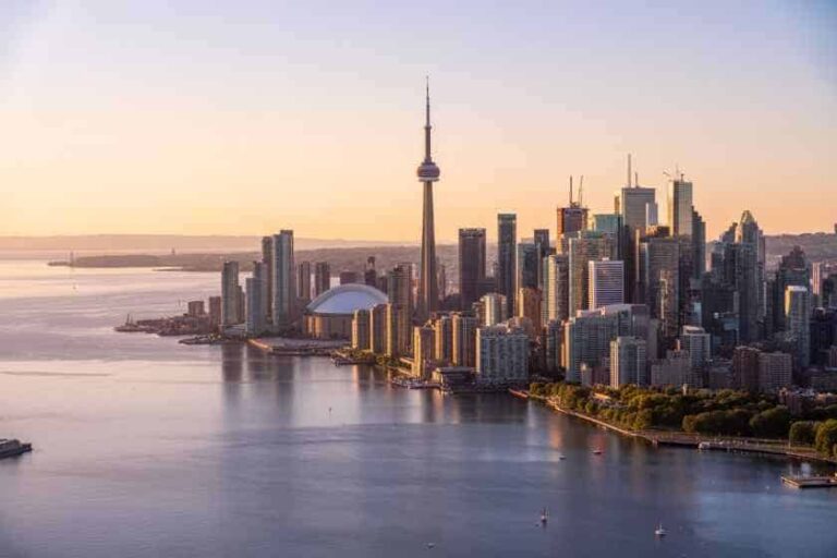 Aerial view of Toronto's downtown skyline at sunset, with the CN Tower and Rogers Centre along the waterfront.