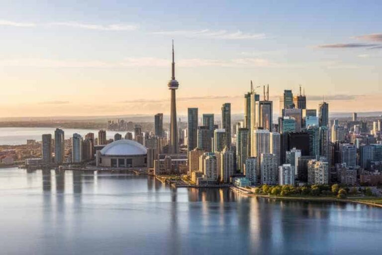 Aerial view of Toronto's skyline at sunset, dominated by the CN Tower and the Rogers Centre by the waterfront.