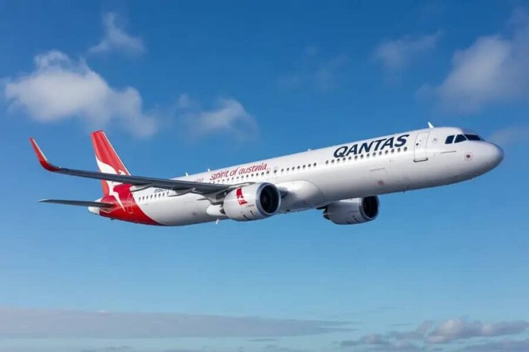 Qantas airliner in flight against a clear blue sky.