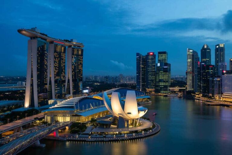 Night view of Singapore's skyline featuring Marina Bay Sands, the ArtScience Museum, and illuminated skyscrapers along the bay.