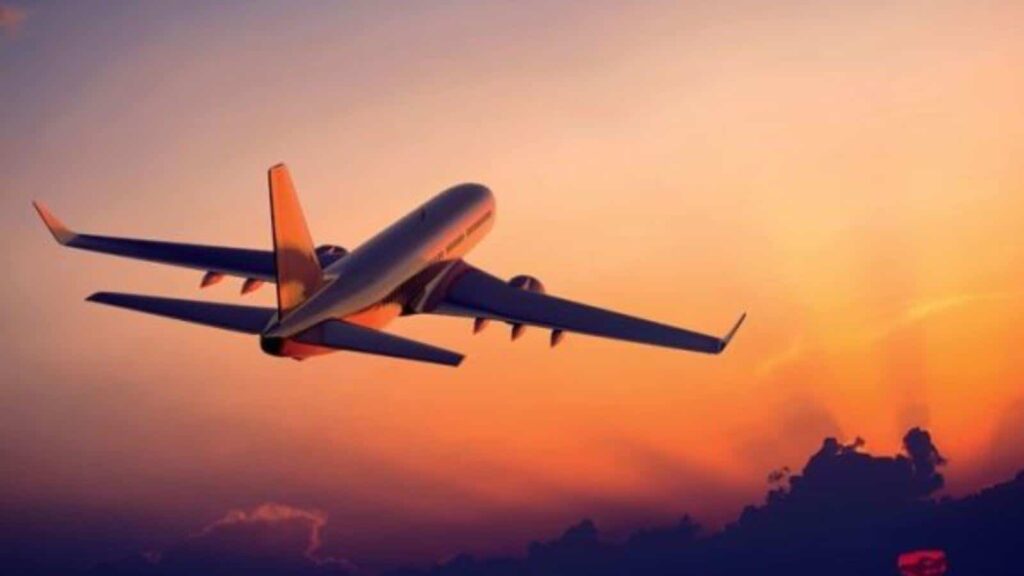 Airplane flying across a sunset sky with orange and purple hues.