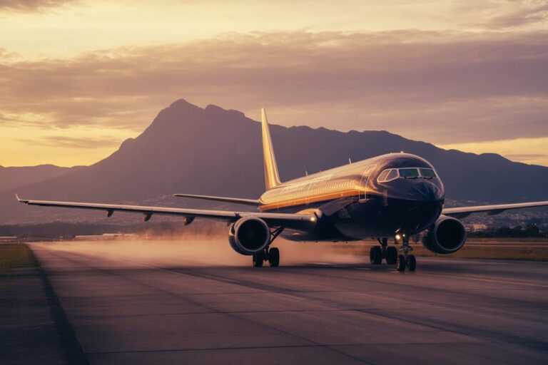 Airliner on a runway at sunset with distant mountains in the background, as it takes off or accelerates.