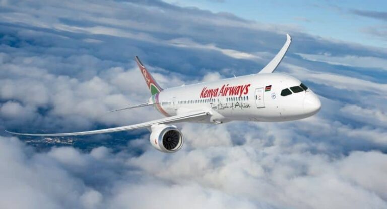 Kenya Airways passenger jet flying above clouds in blue sky, midflight view from the side, with red logo on the fuselage
