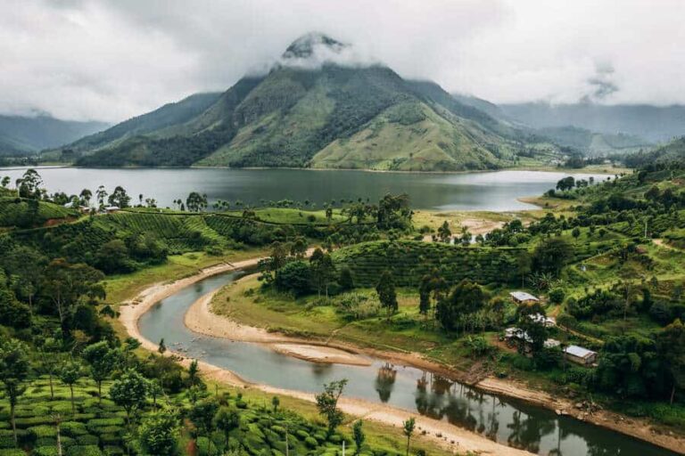 Lush valley with a winding river, green fields, and distant misty mountains.