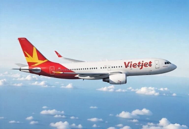 VietJet passenger jet in flight above clouds, with a red and yellow tail design visible.